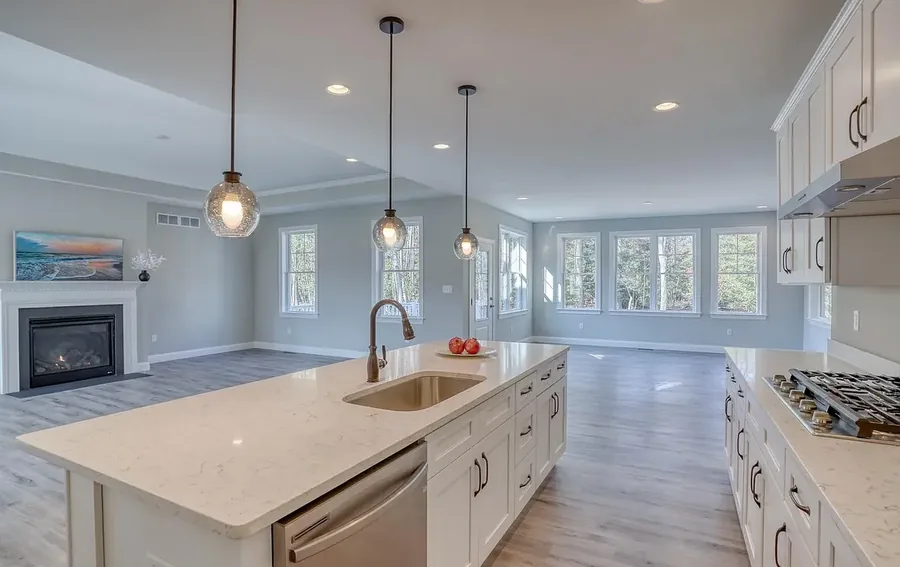 An open kitchen with a quartz island and pendant lighting in a finished custom home.